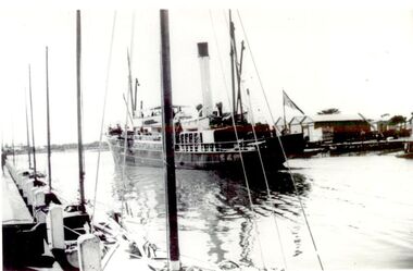 Ship coming into port heading for the turning basin, Shed on Eastern side of the river and couta boats tied up on the western side