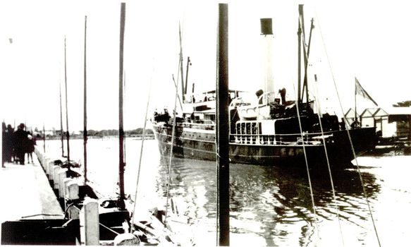 Ship coming up river to berth at wharf harbour sheds on the right