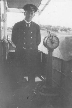Captain John Dowling standing beside the engine order telegraph on the bridge of s.s.CAsino