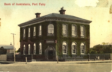 Coloured photograph of the double storied bluestone “ivy” Bank of Australasia with hitching posts either side of corner front door an electricity pole to the left a male, three children and two dogs to the right
