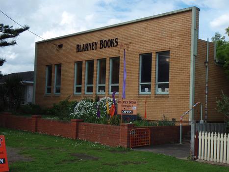 Brick fronted building set back from street with small garden in front entrance to side