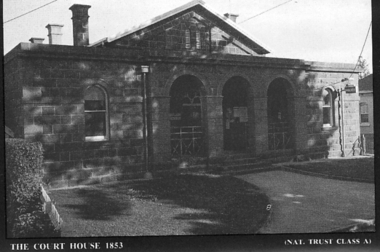 Bluestone building with three arches encasing the portico and a window at each end. 