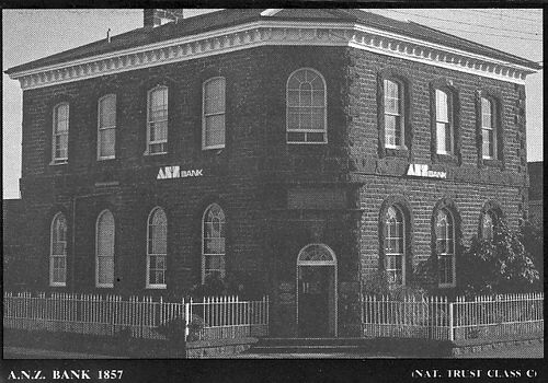Large double story bluestone building with door on corner with metal ‘broomstick’ fencing