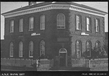Large double story bluestone building with door on corner with metal ‘broomstick’ fencing