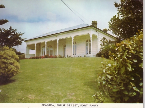 White painted house with bay window on the left, large verandah with 5 wooden posts, arched windows, on hill