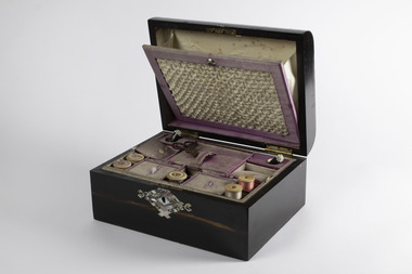 Open sewing box showing insert in lid and sewing items in the top tray
