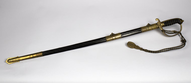 Sword in scabbard with a rope of gold thread ending with a tassel, brass point, brass decoration in centre of scabbard and brass hilt