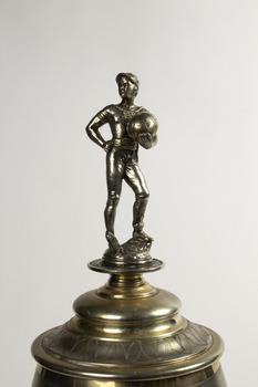 Detail of the footballer figure on the top of the trophy holding a round ball and wearing a cap