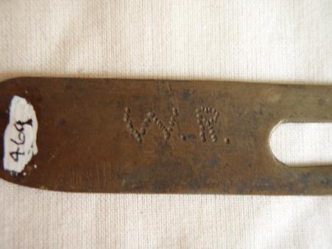 Handmade metal button cleaning helper showing initials hand hammered into metal