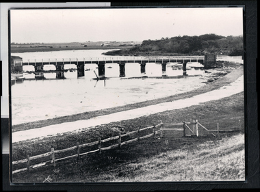 Road bridge at low tide, wooden fence and gate in foreground