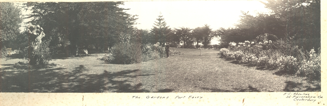 Garden lawns with trees and shrubs either side and  gardener in middloeground