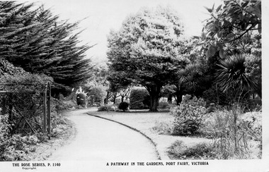 curved pathway running through gardens with a wire support on left for growing flowers on 