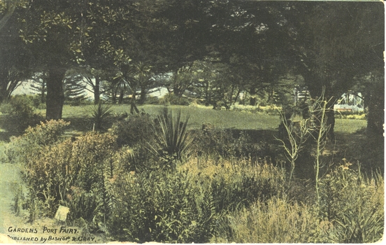 Garden bed beyond which a grassed area surround by trees
