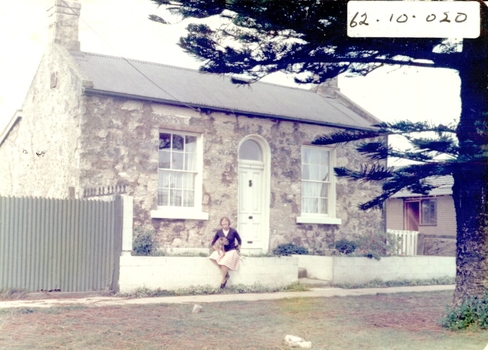 Bluestone and limestone cottage with a stone fence outside and Mary Griffith sitting with her dog out front