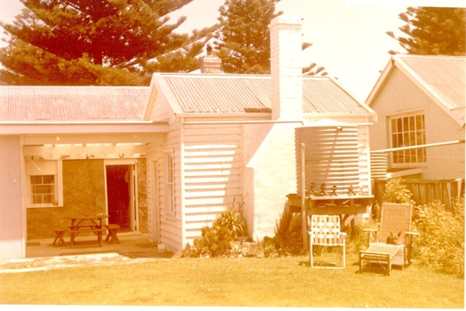 Back yard view of building with water tank and two lounging chairs