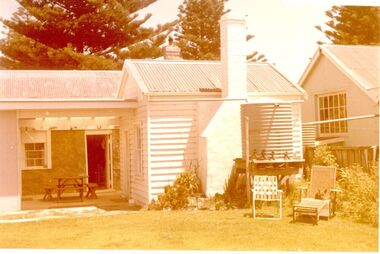 Back yard view of building with water tank and two lounging chairs