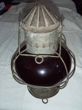 Galvanised metal lamp with a wind proof chimney on top and ruby coloured glass