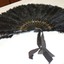 A large fan made from early plastic and feathers with a repeated gold floral design on each slat held together with a brass loop
