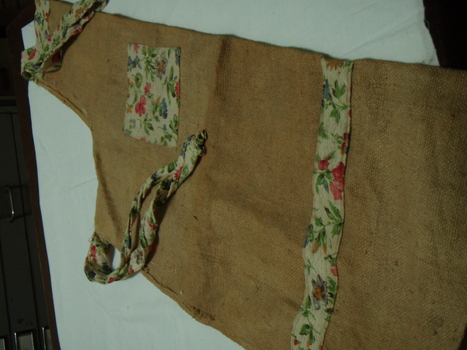hessian bag apron with floral pocket, floral ties and neck piece as well as a strip of floral material around the skirt