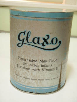 Front of round, blue and grey milk powder tin marked progressive milk food for older infants