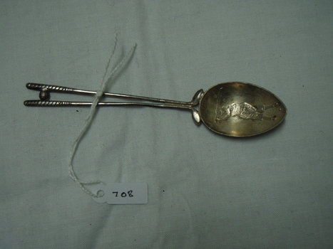 teaspoon with a figure of a golfer engraved in the bowl and two golf clubs forming the handle 