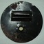 Opposite side of metal circle with round attachment hole and long slit with a cover and wire barrier