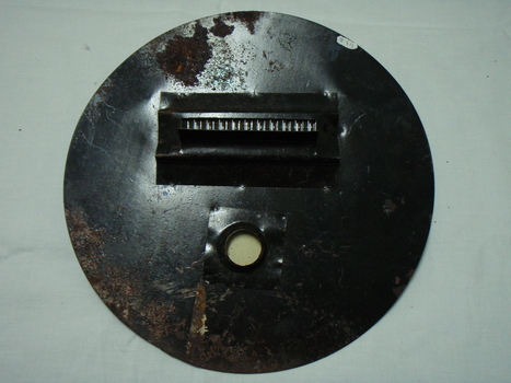 Opposite side of metal circle with round attachment hole and long slit with a cover and wire barrier