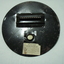 metal circle with light slit and round hole for attachment and paper label of instructions on how to use
