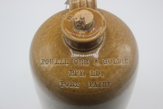 Close up view of inscription on shoulder of clay pottery bottle with modern cork