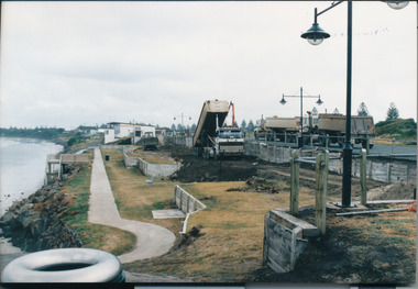 Pathway on edge with embankments to the right and 3 large trucks on the right