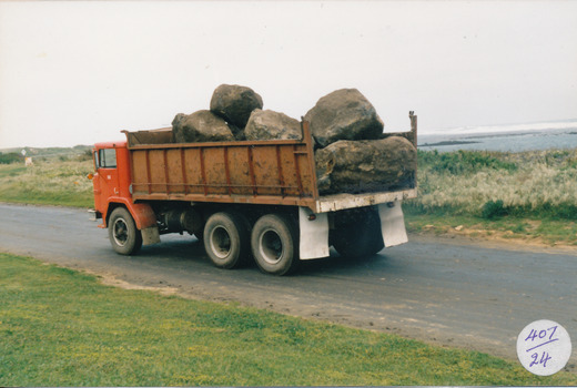 Large tip truck with load of bluestone sea in background