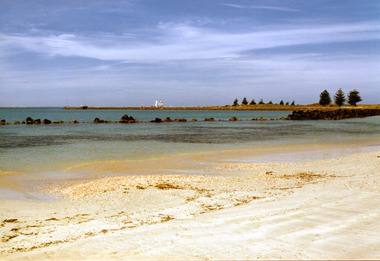 Coloured photograph of the East Beach with the lighthouse and a tall ship in the background