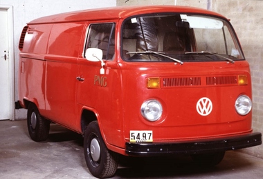 Red van pictured from the front right corner, with rounded features, circular headlights and round white mirrors.
