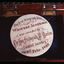 Engraved mother of pearl disc around which paper tape is wound, housed in a wooden presentation box.