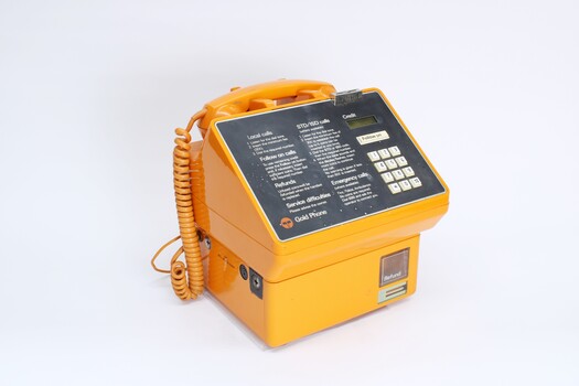 Orange plastic bodied public payphone with grey face and white dial buttons.