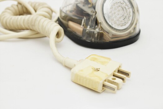 Clear plastic telephone with dial underneath long stemmed handle; colourful electrical wires visible within.
