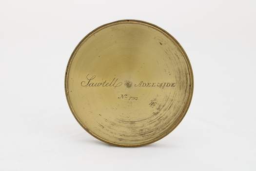 Gold coloured metal compass case with engraved lid; compass face is green printed paper with glass top.