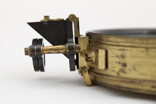 Gold coloured metal compass case with engraved lid; compass face is green printed paper with glass top.