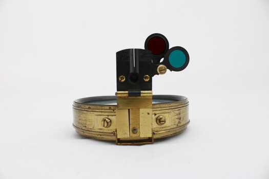 Gold coloured metal compass case with engraved lid; compass face is green printed paper with glass top.