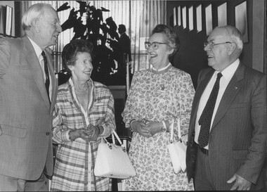 Two men and two women smiling and looking at each other during conversation