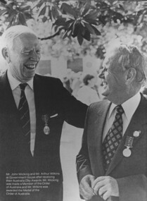 Two men smiling as they face each other after a medal ceremony