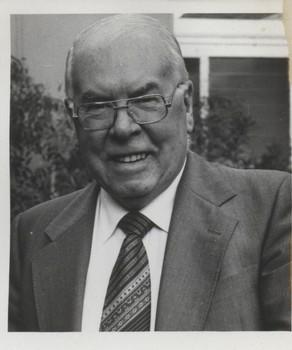 Older man with suit and tie smiles towards camera