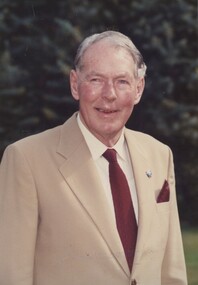 Man wearing beige suit with white shirt and dark red tie and pocket hankie