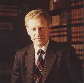 Man in striped suit standing in front of bookcases
