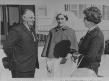 Man smiles as he chats with two woman outside Mirridong