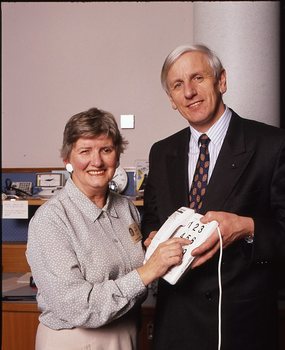 John Cook holding a large button telephone for a woman