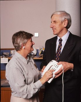 John Cook holding a large button telephone for a woman