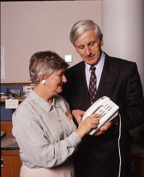 John Cook holding a large button telephone for a woman
