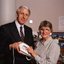 John Cook holding a large button telephone for a woman
