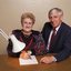 John Cook sitting next to a woman writing on a thickly lined notepad